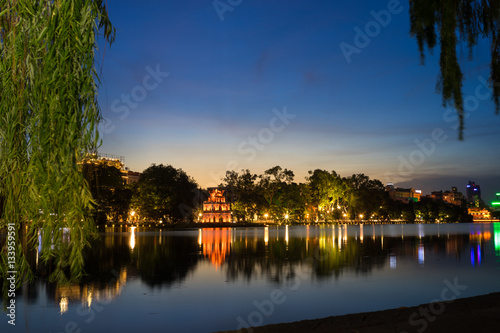 Hoan Kiem lake ( Ho Guom, Sword lake), the center of Hanoi capital, Vietnam at twilight. Willow branches on foreground