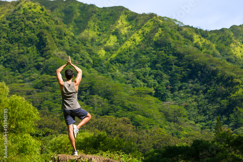 Man doing yoga on a mountain top. 