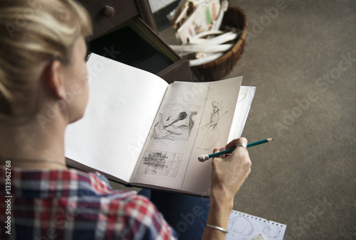 Female artist looking at sketches in book while sitting at home photo