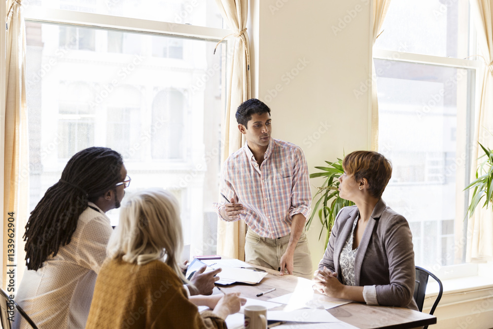 Businessman explaining strategy to colleagues during meeting in office Businessman explaining strategy to colleagues during meeting in office