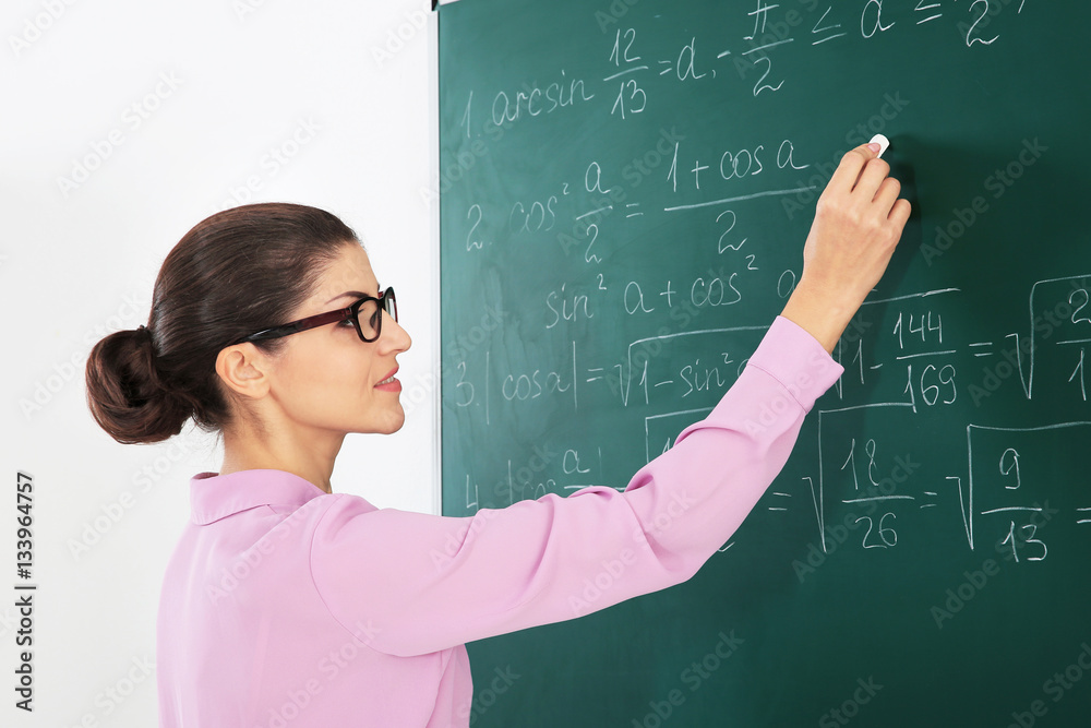 Young female teacher beside blackboard