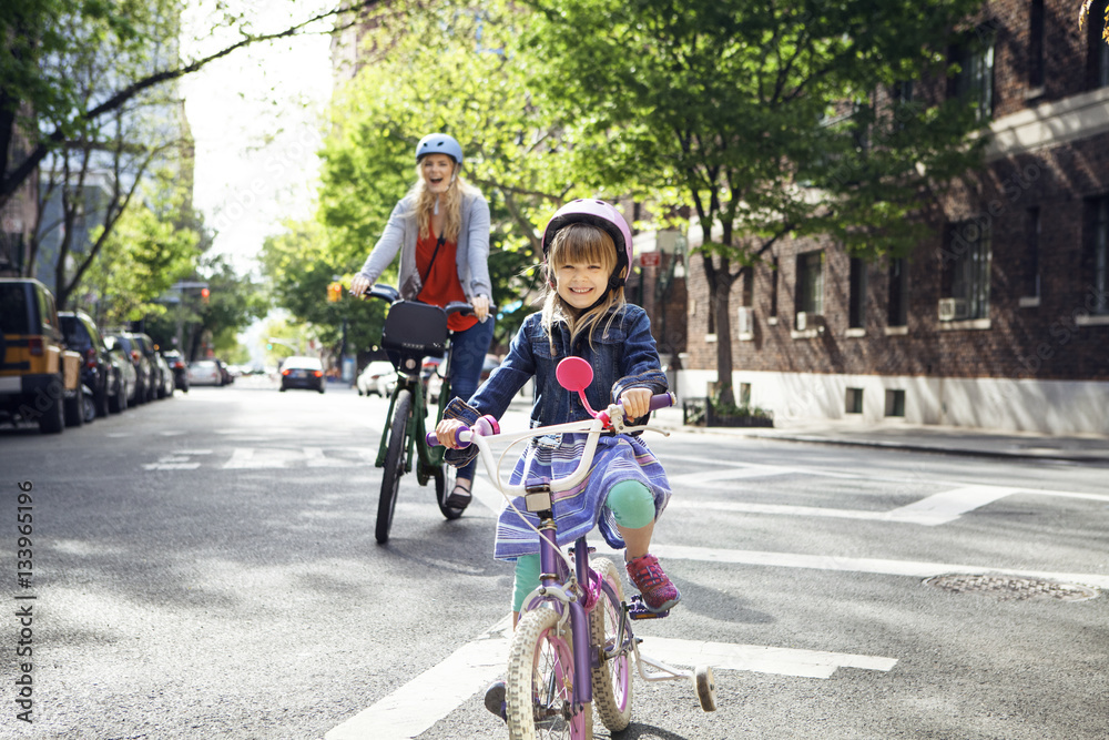Portrait of happy mother and daughter riding bicycles on street Portrait of happy mother and daughter riding bicycles on street
