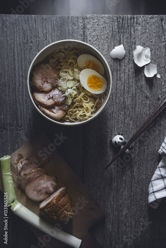Overhead view of char sui pork and ramen noodles with egg on wooden table