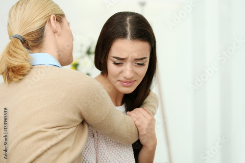 Woman hugging her depressed friend at home