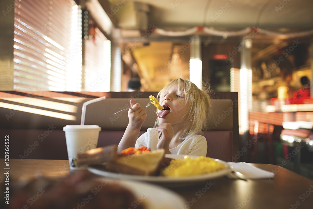 Girl eating food while sitting at restaurant Girl eating food while sitting at restaurant