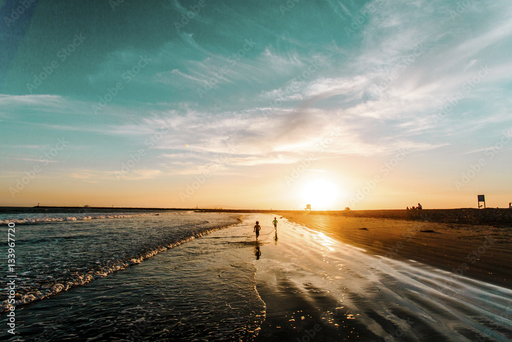 Rear view of people running on shore during sunset Rear view of people running on shore during sunset