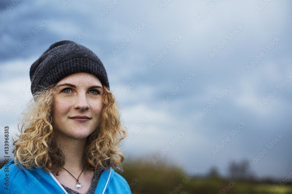 Thoughtful female athlete looking away against cloudy sky