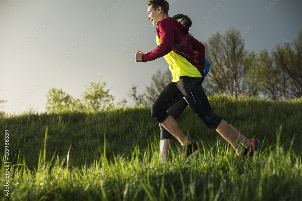 Side view of athletes running on grassy field during sunset Side view of athletes running on grassy field during sunset