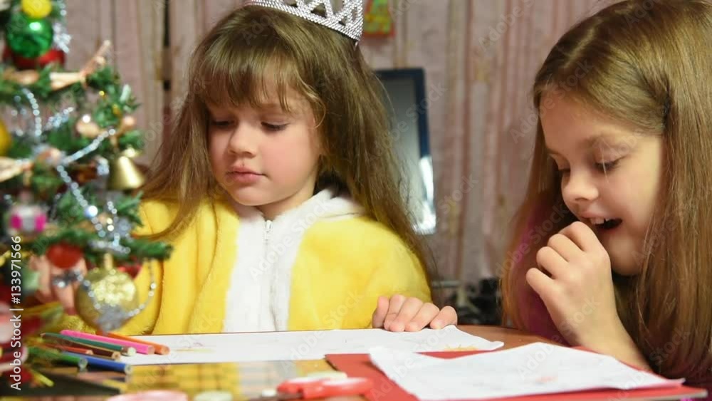 One girl draws a picture in the New Year's Eve, another fun watching her One girl draws a picture in the New Year's Eve, another fun watching her