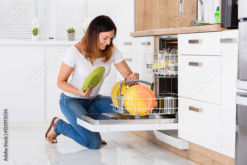 Woman Arranging Plates In Dishwasher photo
