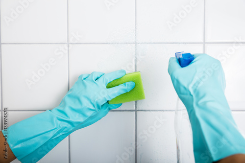 Close-up Of Person Cleaning The Tiled Wall
