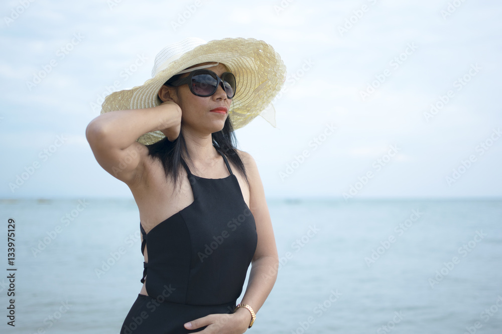Sexy woman with black dress posing on the beach