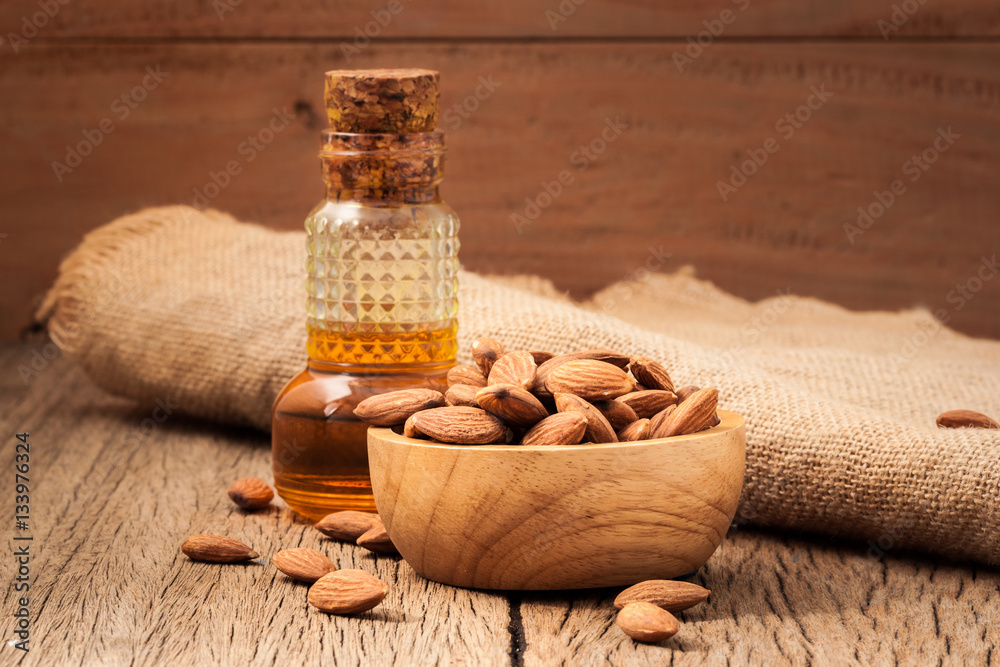 almonds in a cup of oil in a glass timber on the old wooden floor boards as a backdrop. almonds in a cup of oil in a glass timber on the old wooden floor boards as a backdrop.