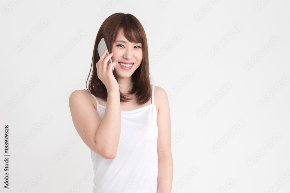 若い女性が、スマートフォンを操作しています。この画像の背景は白です。 若い女性が、スマートフォンを操作しています。この画像の背景は白です。