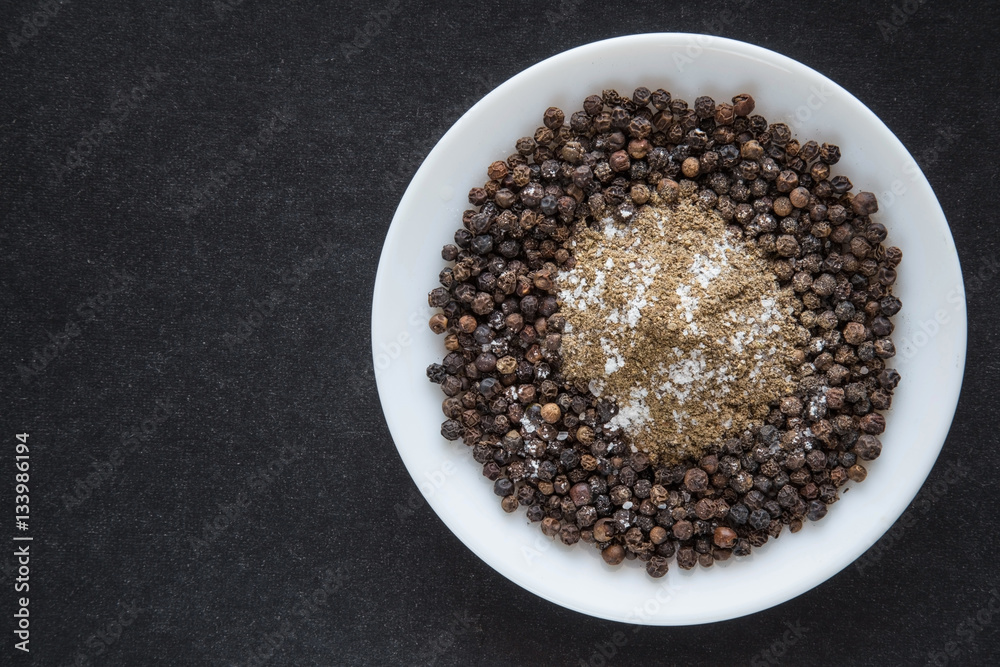 Black pepper grains with ground pepper and a little bit salt in the