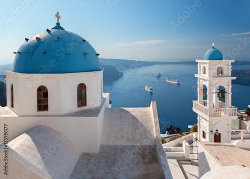 Santorini - The tower of Anastasi church in Imerovigli with the cruises in background.