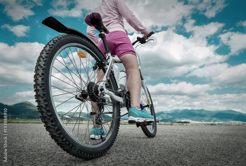 Fototapeta premium Beautiful woman in helmet and glasses stay on the bicycle under