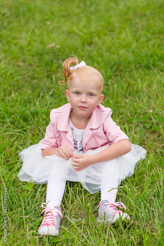 A cute little girl in a beautiful dress and sneakers playing in A cute little girl in a beautiful dress and sneakers playing in