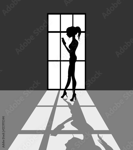 Silhouet van vrouw met mobiele telefoon voor een venster photo