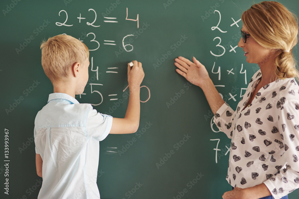 Student boy with chalk next to the chalkboard Student boy with chalk next to the chalkboard