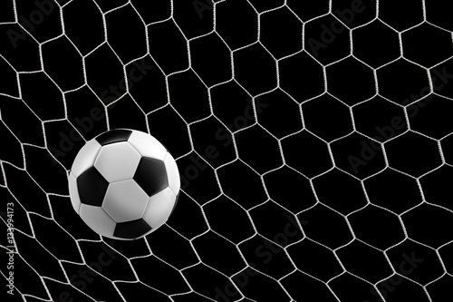 soccer ball in goal net isolated on black background © neosiam