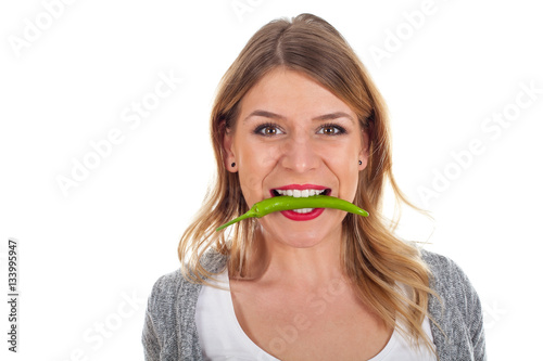 Beautiful girl biting of a hot paprika