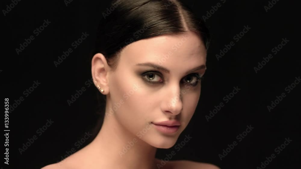 Fashion brunette standing on black wall background in studio, very close-up Fashion brunette standing on black wall background in studio, very close-up