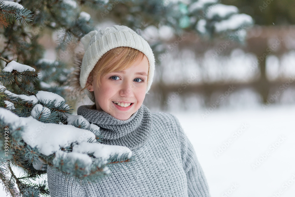 Beautiful girl in a white hat and mittens in the winter snowy fo Beautiful girl in a white hat and mittens in the winter snowy fo