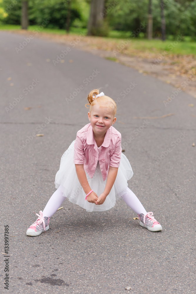A cute little girl in a beautiful dress and sneakers playing on A cute little girl in a beautiful dress and sneakers playing on