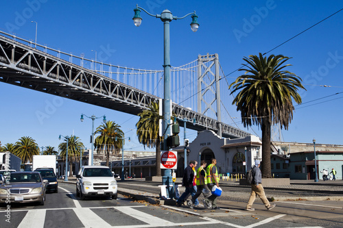 Canvas Print Workers crossing street in San Francisco under Oakland Bridge