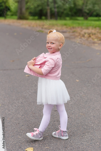 A cute little girl in a beautiful dress and sneakers playing on