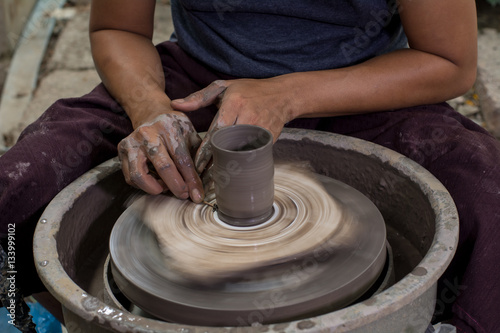 Hands of potter do a clay cup