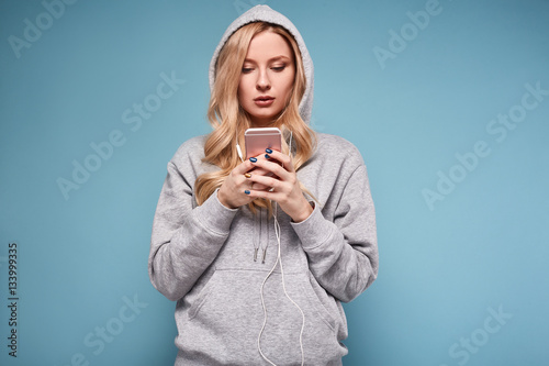 Cute positive blonde woman in hoodie listening music © micro