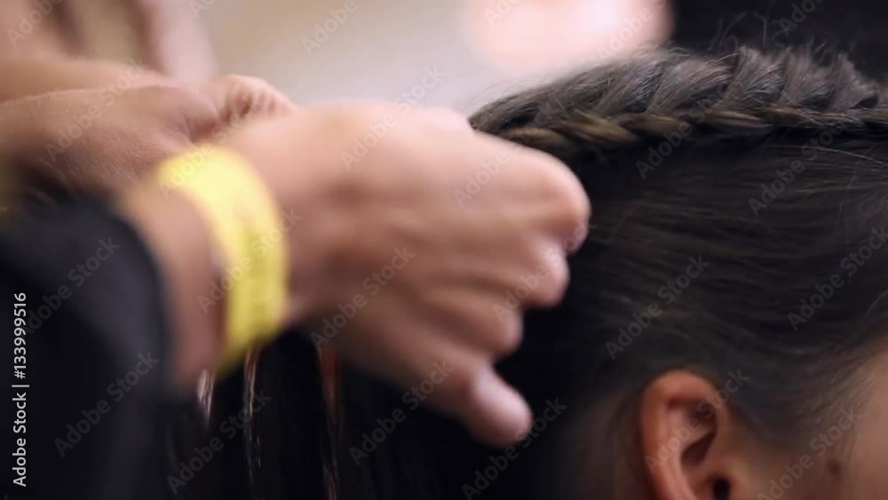 Hairdresser makes hairstyle for the model close-up. Preparing for the fashion show. Dressing room for models. Weaving hair braids. Hairdresser makes hairstyle for the model close-up. Preparing for the fashion show. Dressing room for models. Weaving hair braids.