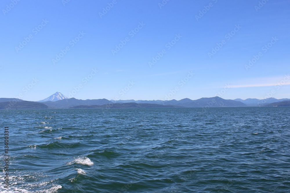 Ocean waves on a sunny day with a volcano on the horizon