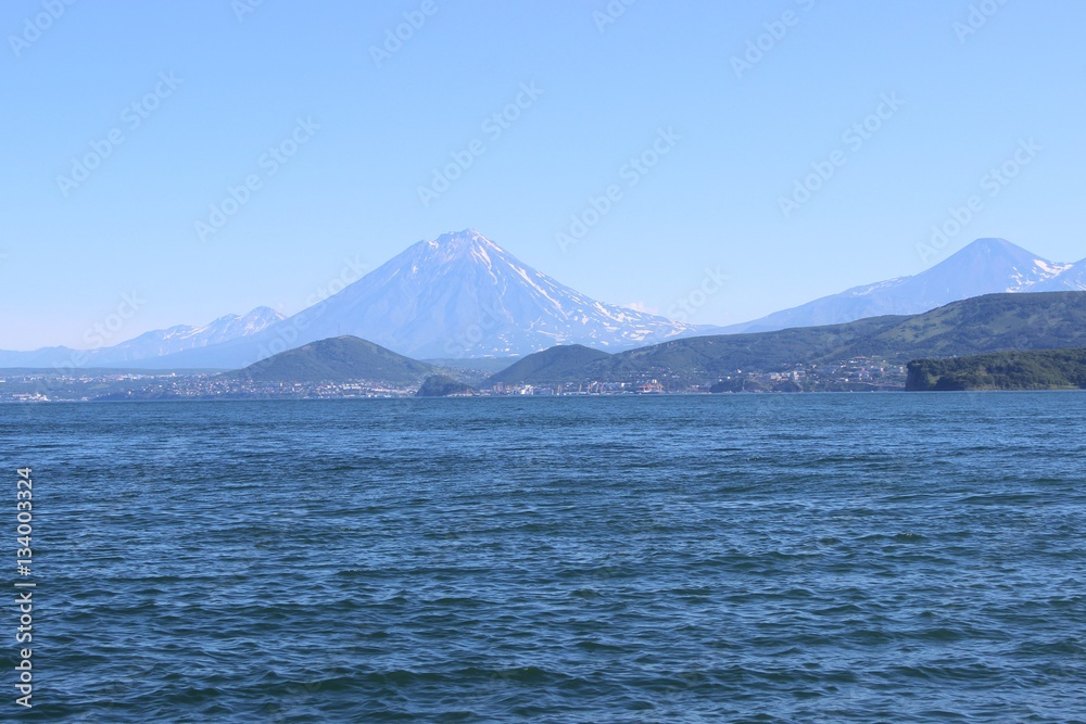 Ocean waves on a sunny day with a volcano on the horizon