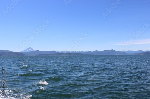 Ocean waves on a sunny day with a volcano on the horizon