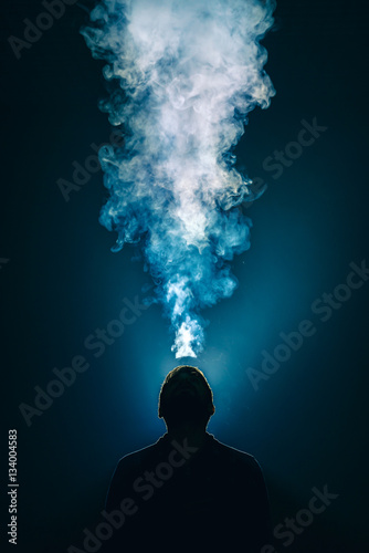 The man smoke an electronic cigarette on the background of bright light