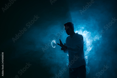 The man smoke an electrical cigarette with a ring on the dark background