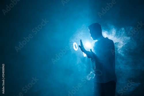 The man smoke an electrical cigarette with a ring on the dark background