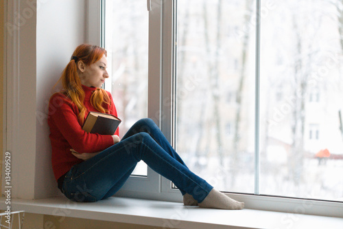 girl sitting on the windowsill, and draws on the glass.