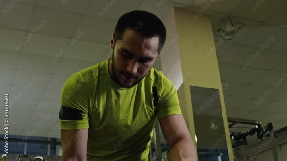 Man with artificial foot sitting on bench in the gym and lifting dumbbell with one arm Man with artificial foot sitting on bench in the gym and lifting dumbbell with one arm