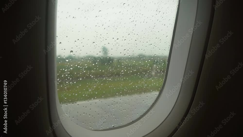 Rain drops on the window of the plane in rainy weather..Rain drop on the transparent glass window of airplane with blurred. 4K video Travel concept. Rain drops on the window of the plane in rainy weather..Rain drop on the transparent glass window of airplane with blurred. 4K video Travel concept.