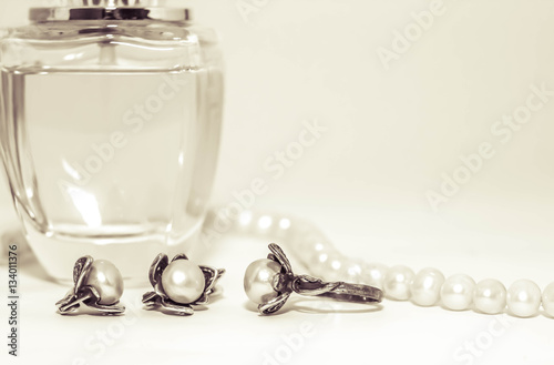 Красивый стеклянный флакон с женскими духами.  украшение из жемчуга серьги и кольцо.