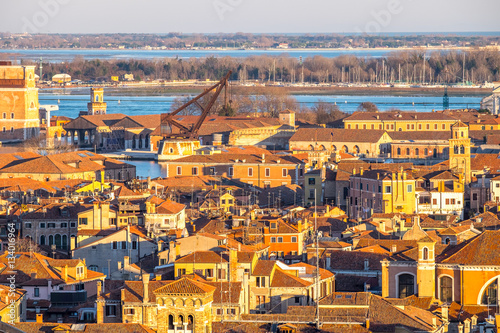 Aerial view of Venice, Italy, at sunset with rooftops of building, the sea and warm sunlight. © Augustin Lazaroiu