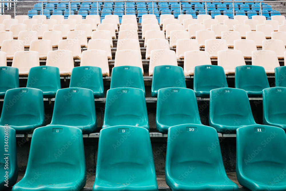 Part of a tribune of old stadium with the seats painted in different colors Part of a tribune of old stadium with the seats painted in different colors