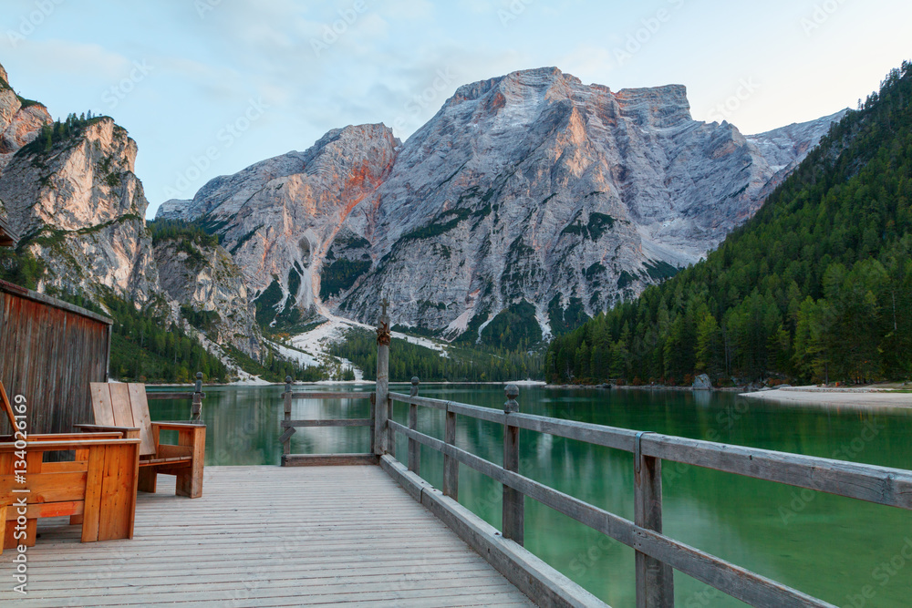 Old wooden house on the Braies lake in the background of Seekofe