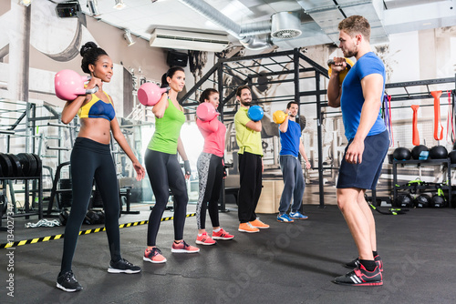 Men and women with coach at kettlebell functional training