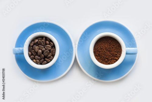 two blue macro coffee espresso cups with the fresh coffee beans and with a ground coffee on the white background