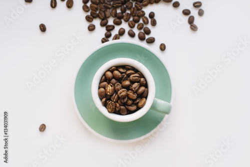 fresh morning coffee beans in a small espresso cup on a white background